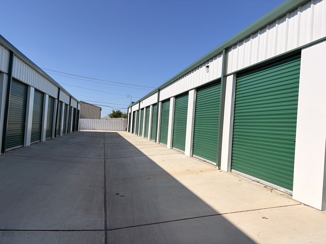 Wide concrete drive aisle between green-door storage buildings at A-1 Self Storage on W Pafford Street in Fort Worth