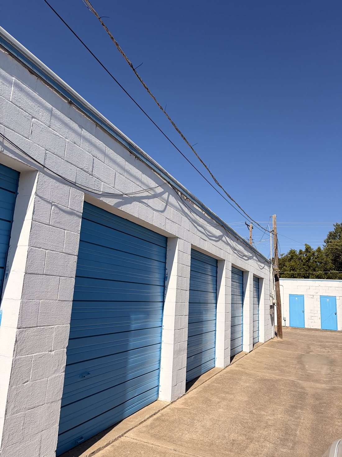 Drive-up storage units with blue roll-up doors at A-Thrifti Self Storage on 8th Avenue in Fort Worth
