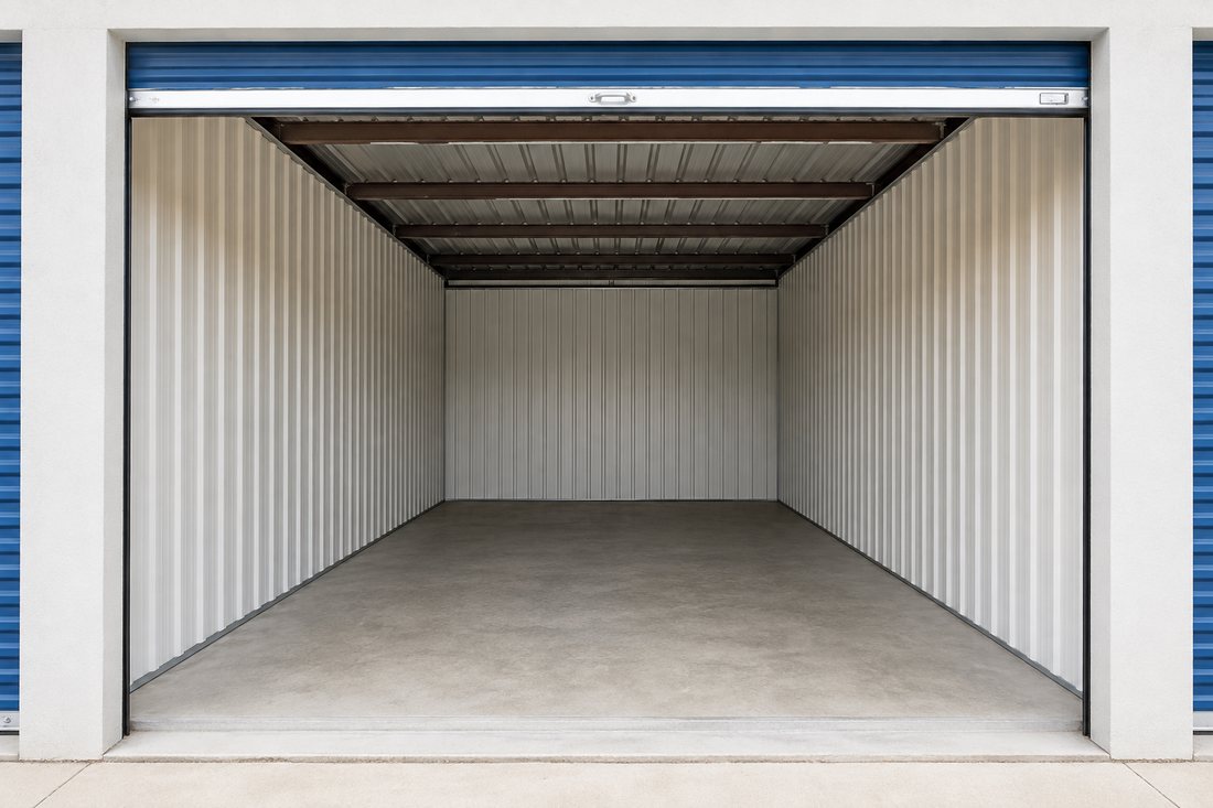 Interior of an empty drive-up storage unit with a clean concrete floor and open roll-up door